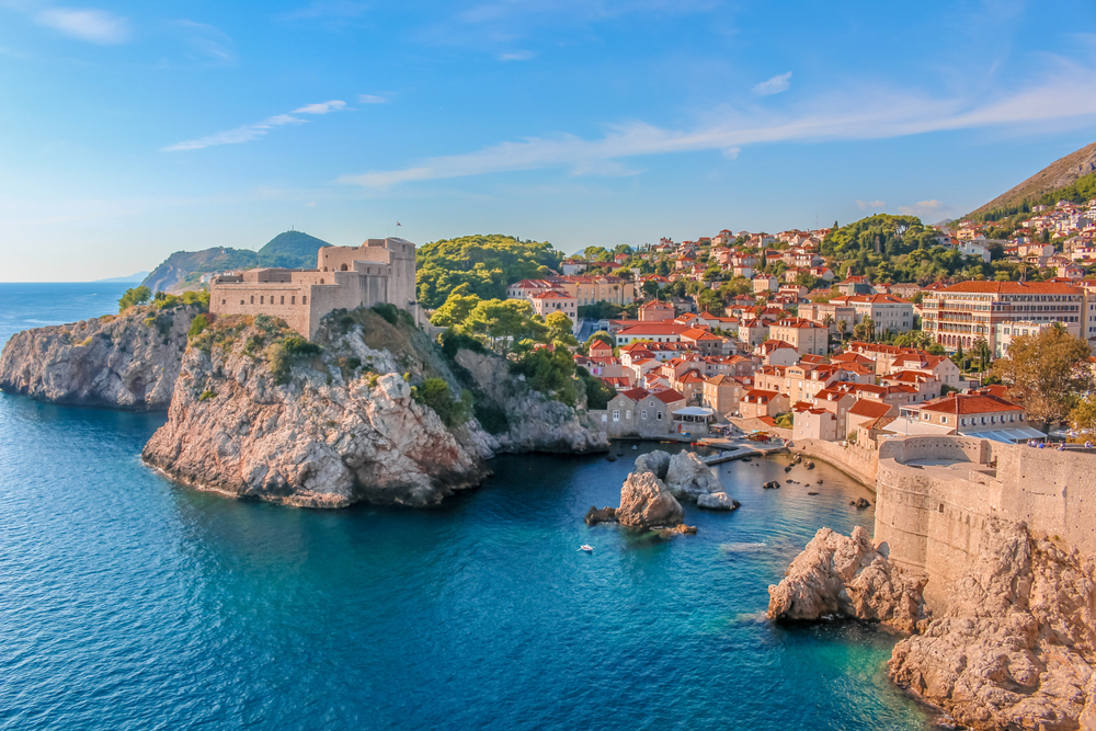A rocky cliffside city with terracotta colored buildings and bright blue water