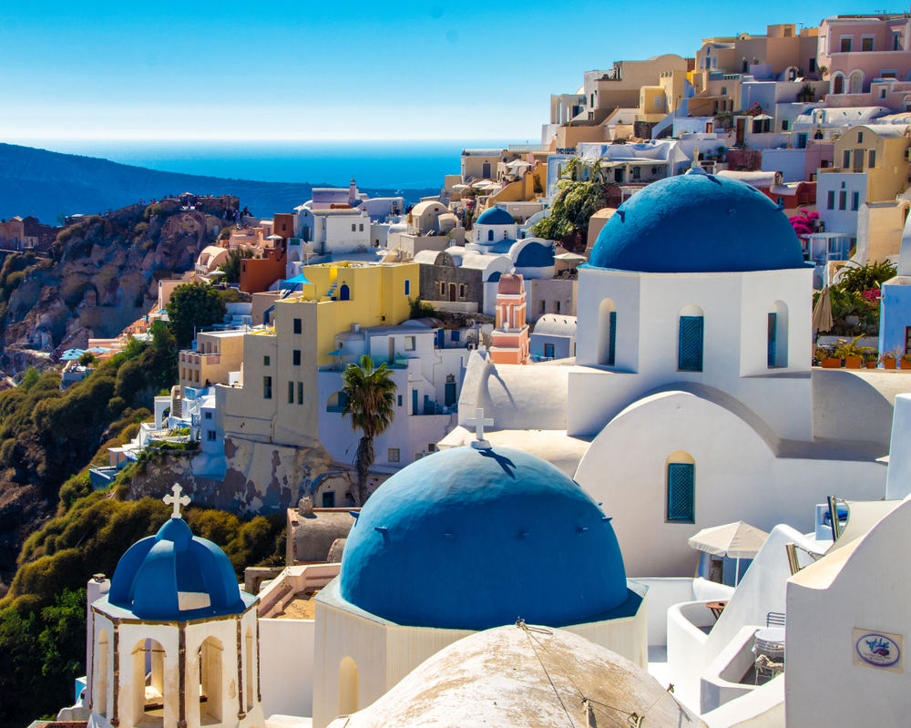 A classic Greek seaside village on a cliff with colorful buildings, best places to visit in Europe in May