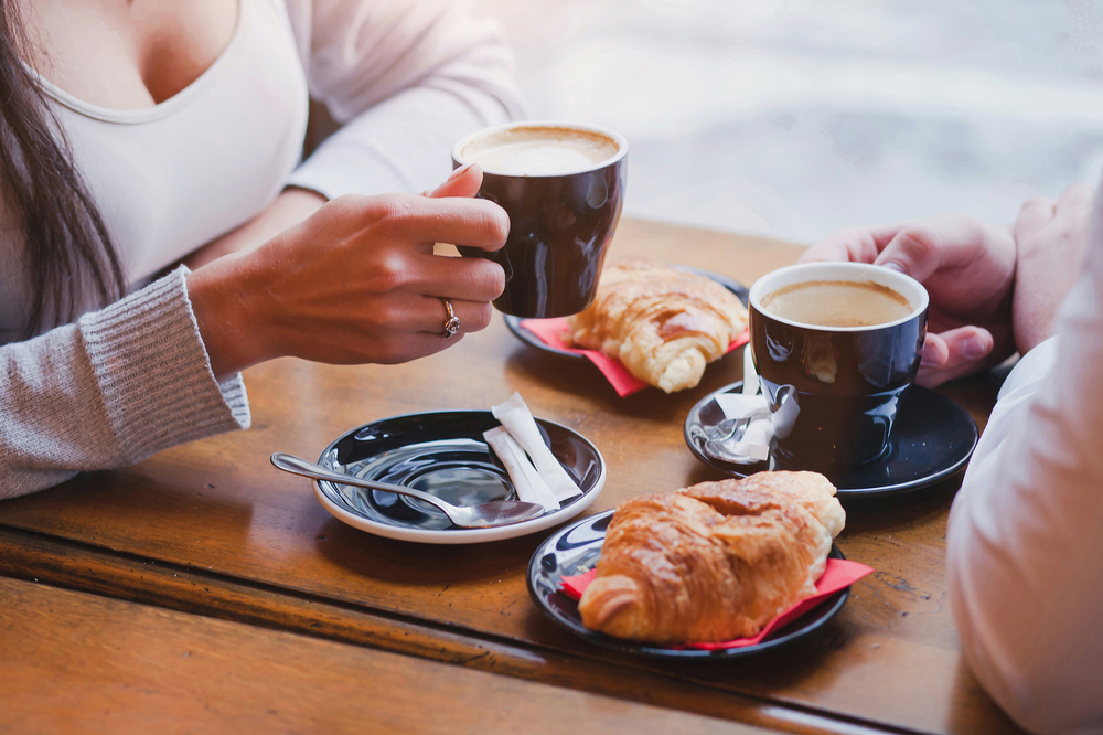 A couple sitting at a table with coffee and French pastries