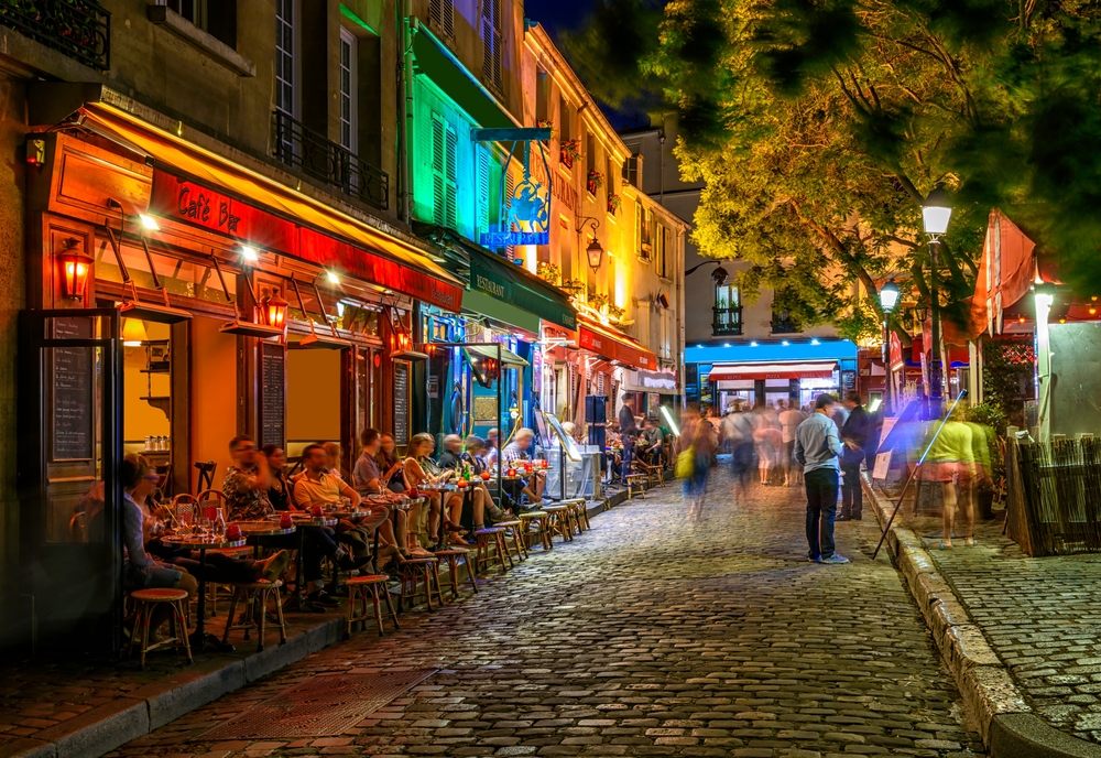 The Marais district in a must visit on your 2 days in Paris Itinerary, the liverly street with lights and Parians enjoying the evening out