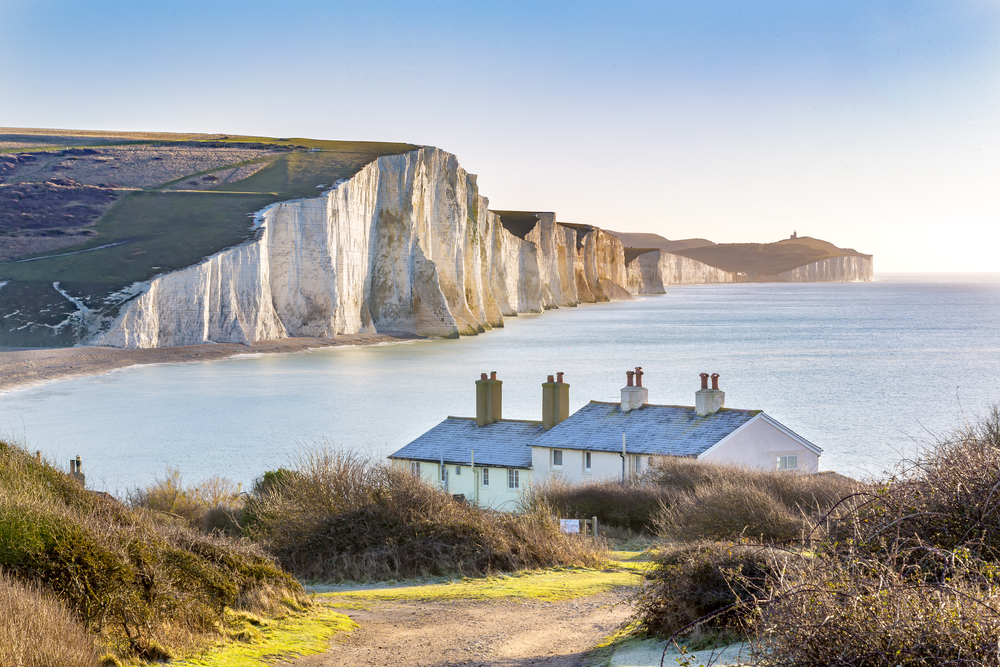 The Coast Guard Cottages & Seven Sisters Chalk Cliffs. It's a frosty day with cottages in the foreground and the cliffs are in the background. 