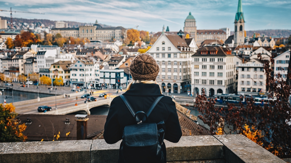 a girl over looking a city in Europe, she is dressed very warmly and has a cute black jacket on. 