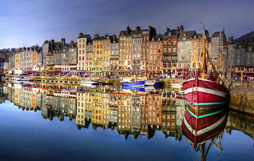 Boast in the harbor with houses behind them in one of the small towns in France. 