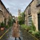 a girl in brown dress standing on onne of the many streets in Edinburgh