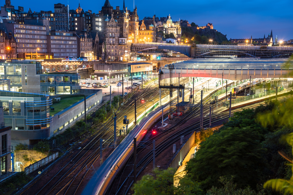 The city of Edinburgh at night time with train tracks and tram way of Waverly Station