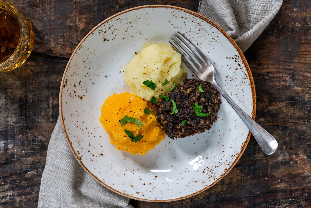 A traditional Scottish dish of Haggis on a plate with potatoes and veggies is a must-try on your 2 days in Edinburgh itinerary-