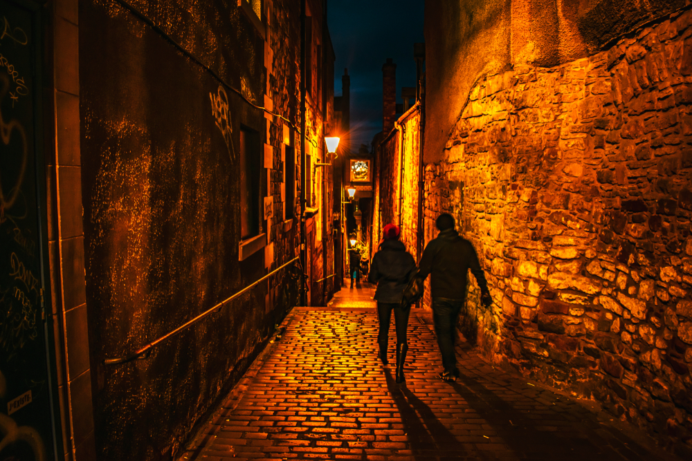 a couple walking along the Royal Mile at night going into the underground