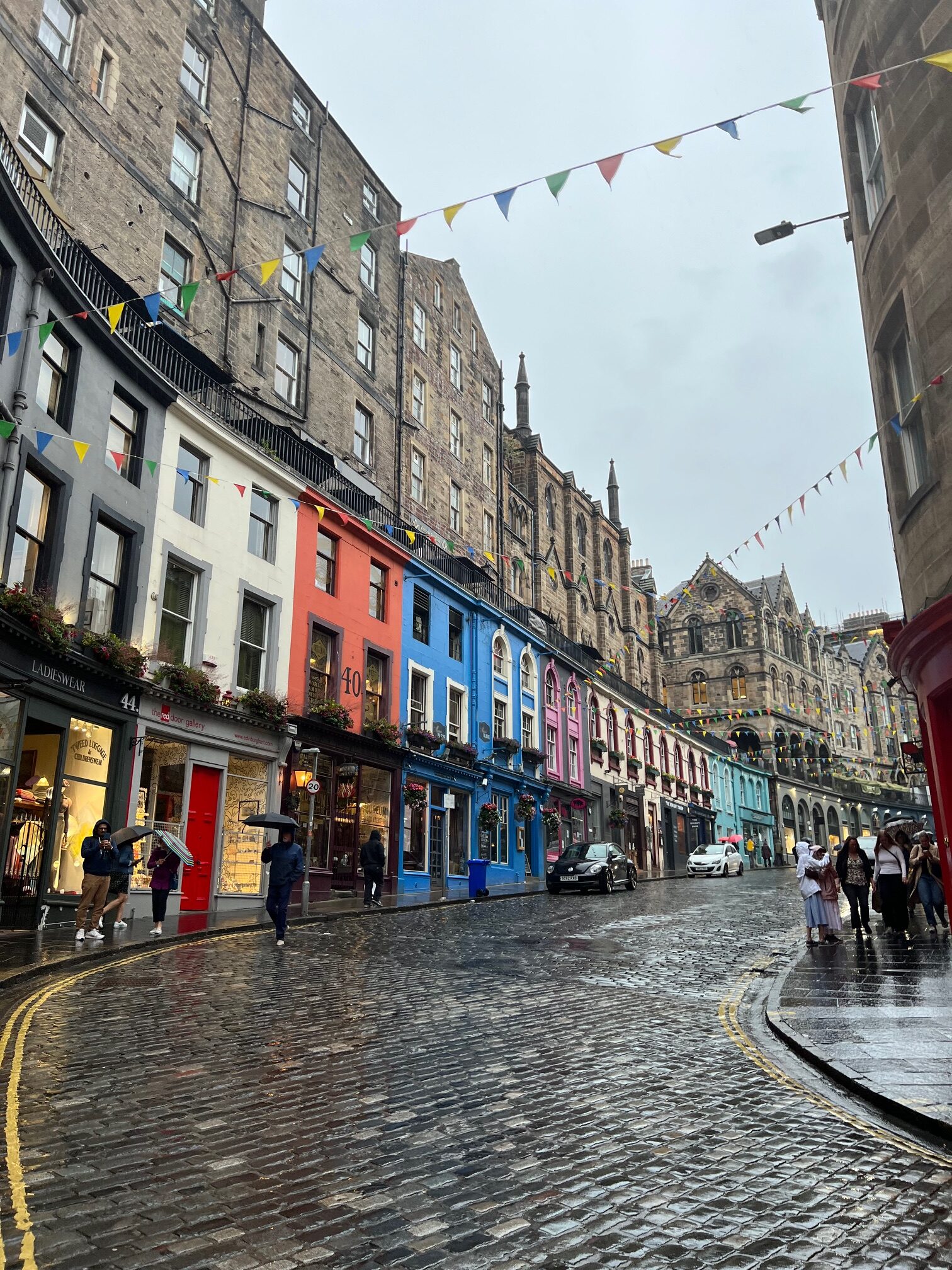 One of the prettiest streets in Edinburgh Victoria Street with curved cobblestone street with buildings and flags