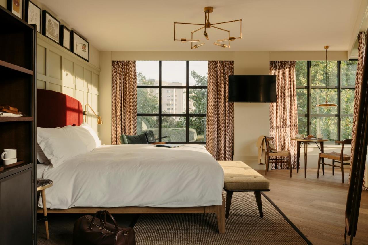 The bedroom at Kimpton with large windows and table and warm and inviting large space