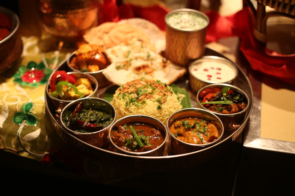 an Indian sampler platter with a variety of dishes with naan bread and other dishes