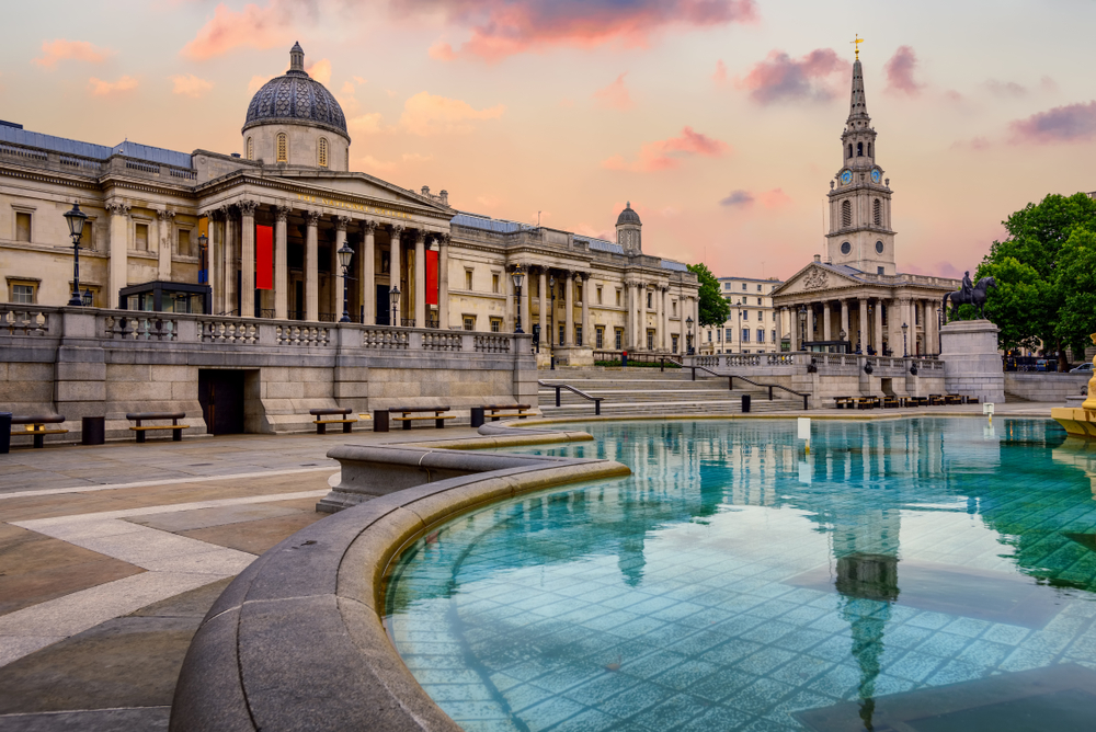 The exterior of the National Gallery with reflecting pond at sunset. 