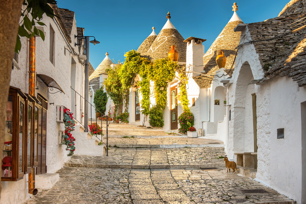 Golden hour over a stone street in Alberobello with the white, cone-shaped Trulli.