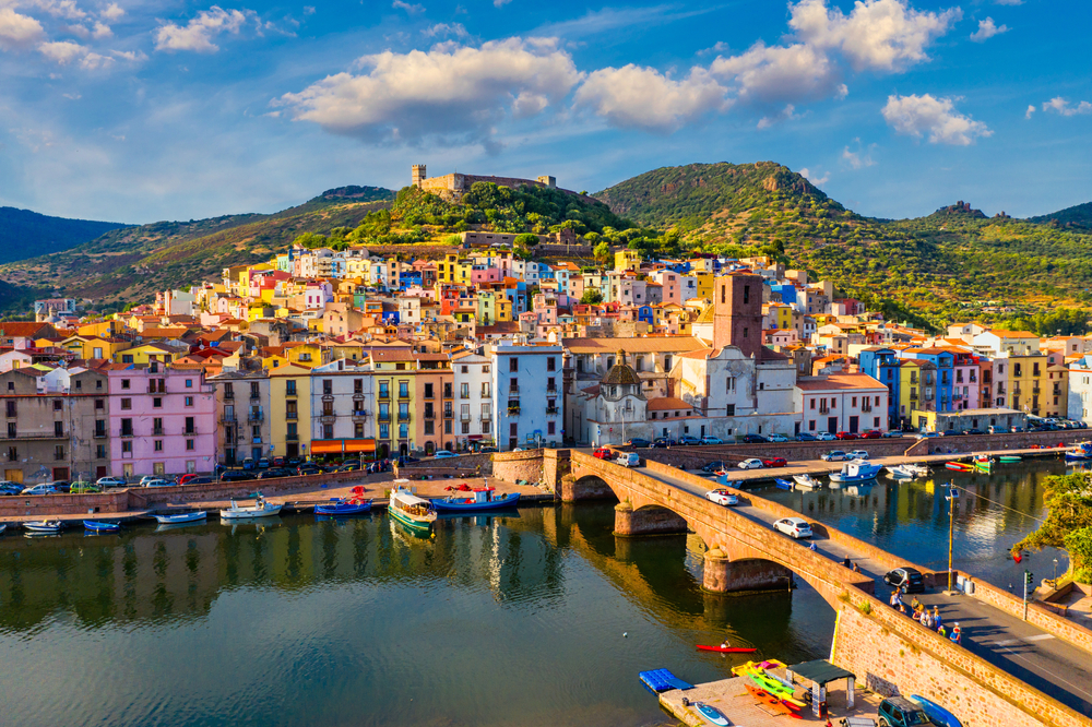 View overlooking the river and a bridge leading to colorful buildings in Bosa.