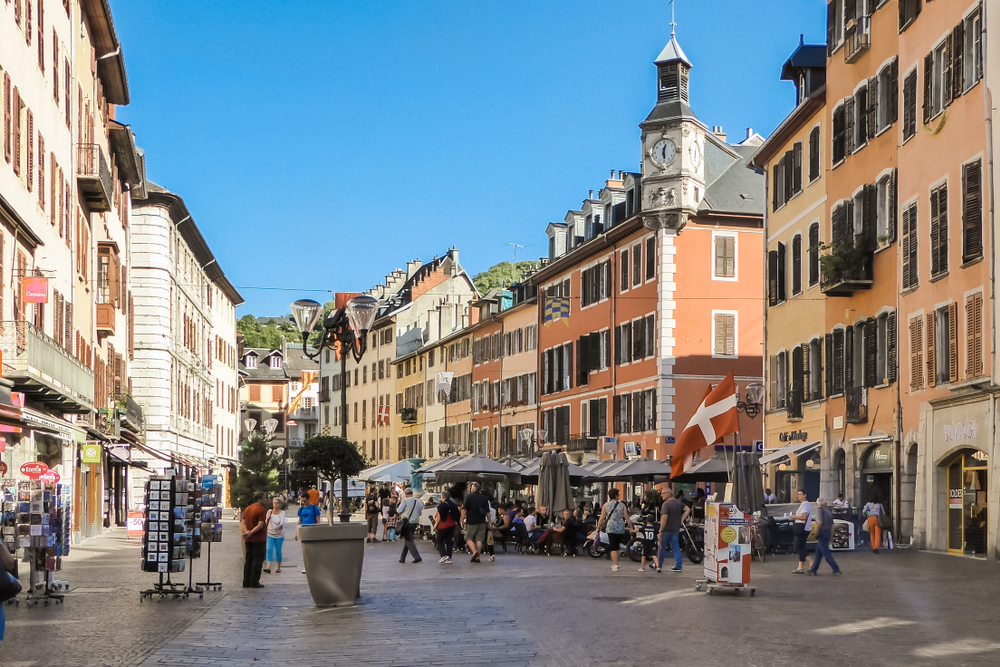 Pedestrian street with people walking around shops and restaurants on a France road trip.