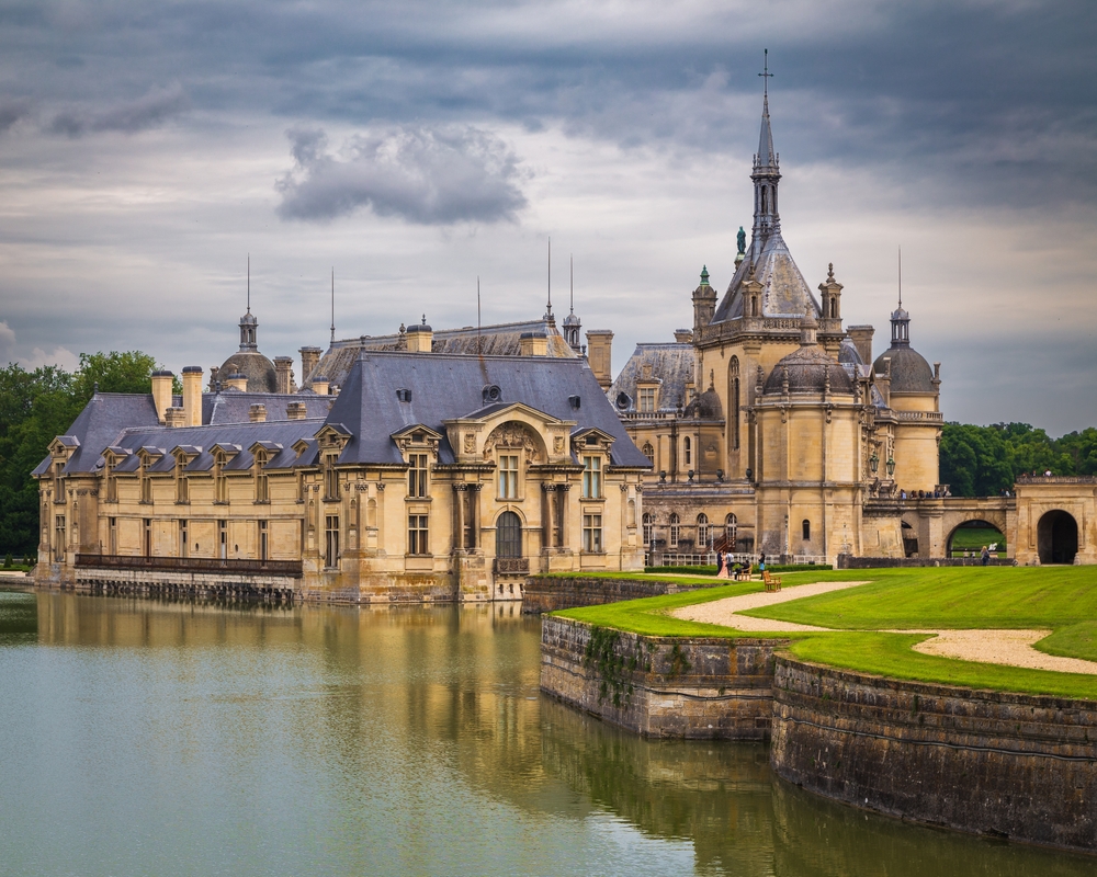 Regal Château de Chantilly set on water on a cloudy day during a France road trip.