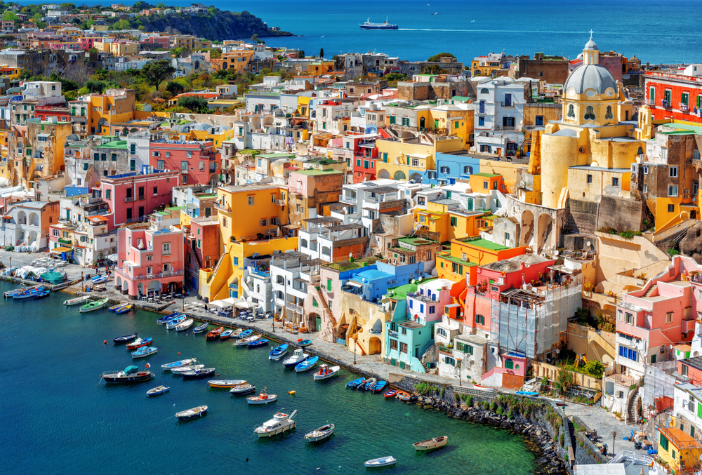Looking down at the colorful, stacked buildings of Corricella with boats in the harbor.