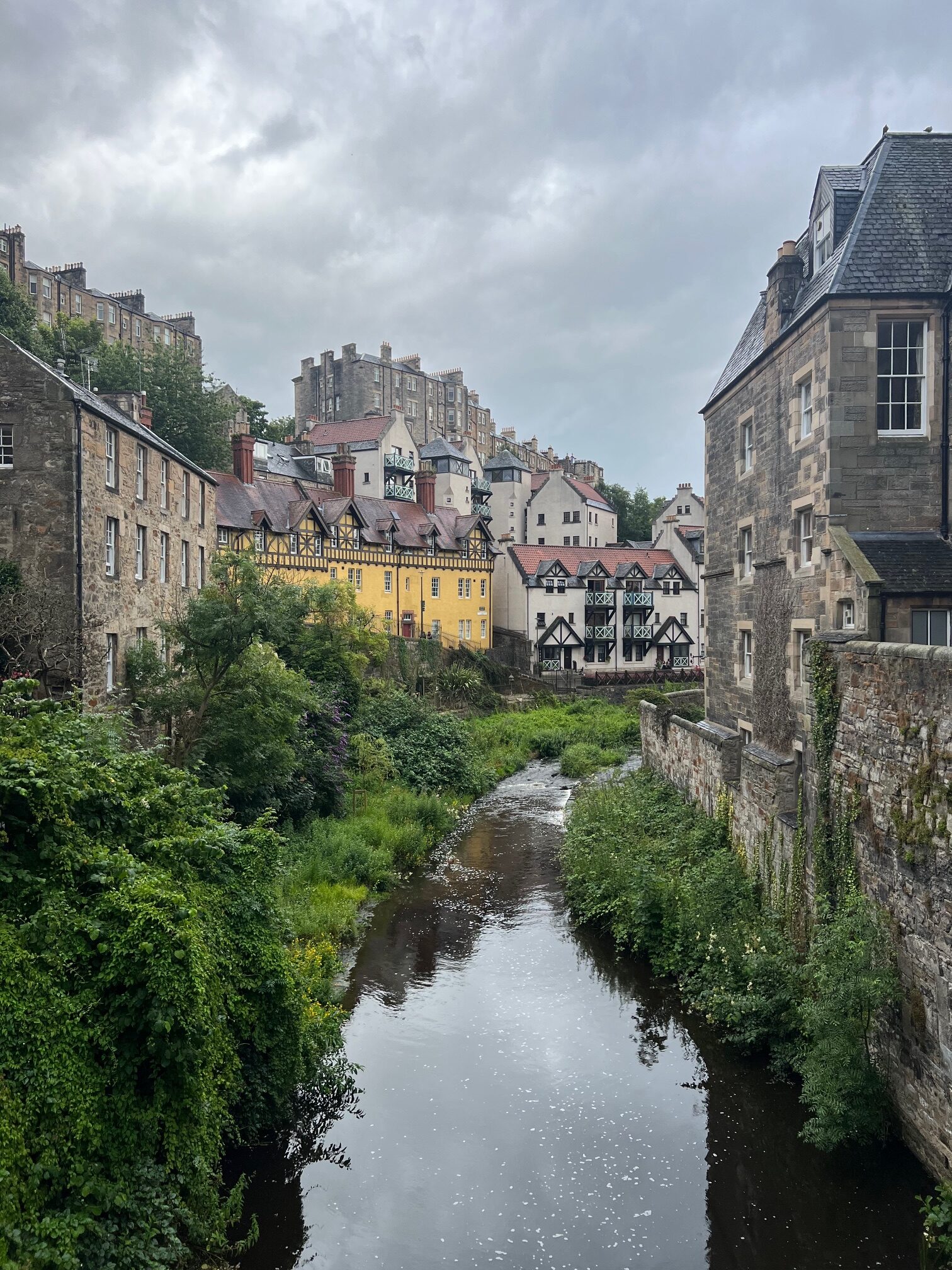 Dean Village in Edinburgh Scotland with yellow and brown houses with river running through them 