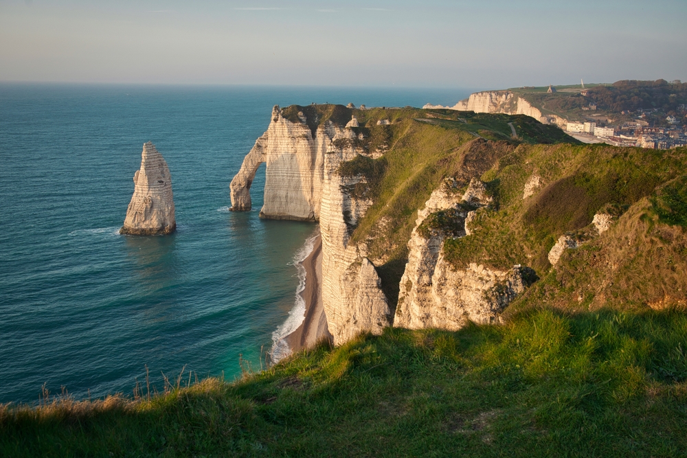 View looking down over white cliffs in Étretat with a sea pillar and arch.