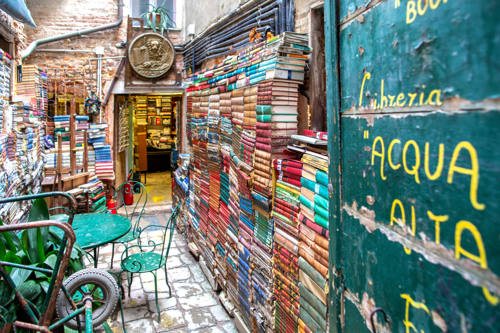 Courtyard with walls of books and a metal table and chairs at Libreria Acqua Alta, one of the most Instagrammable places in Venice.