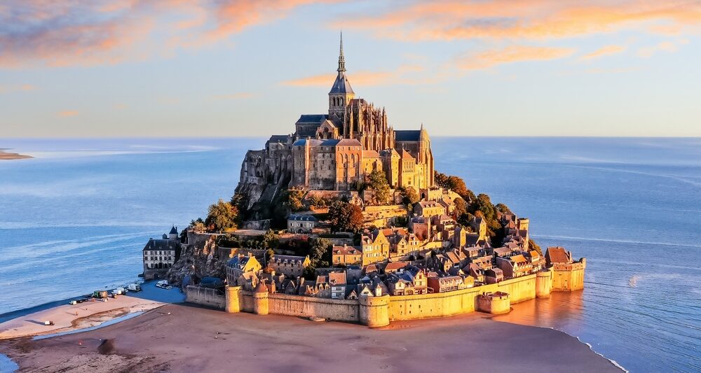 island of mont st michel in france at sunset with water surrounding