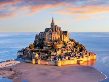 island of mont st michel in france at sunset with water surrounding