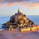 island of mont st michel in france at sunset with water surrounding