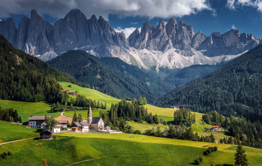 Beautiful view of the small town of Santa Maddalena nestled in the rolling green hills at the base of the rugged Dolomite mountains.