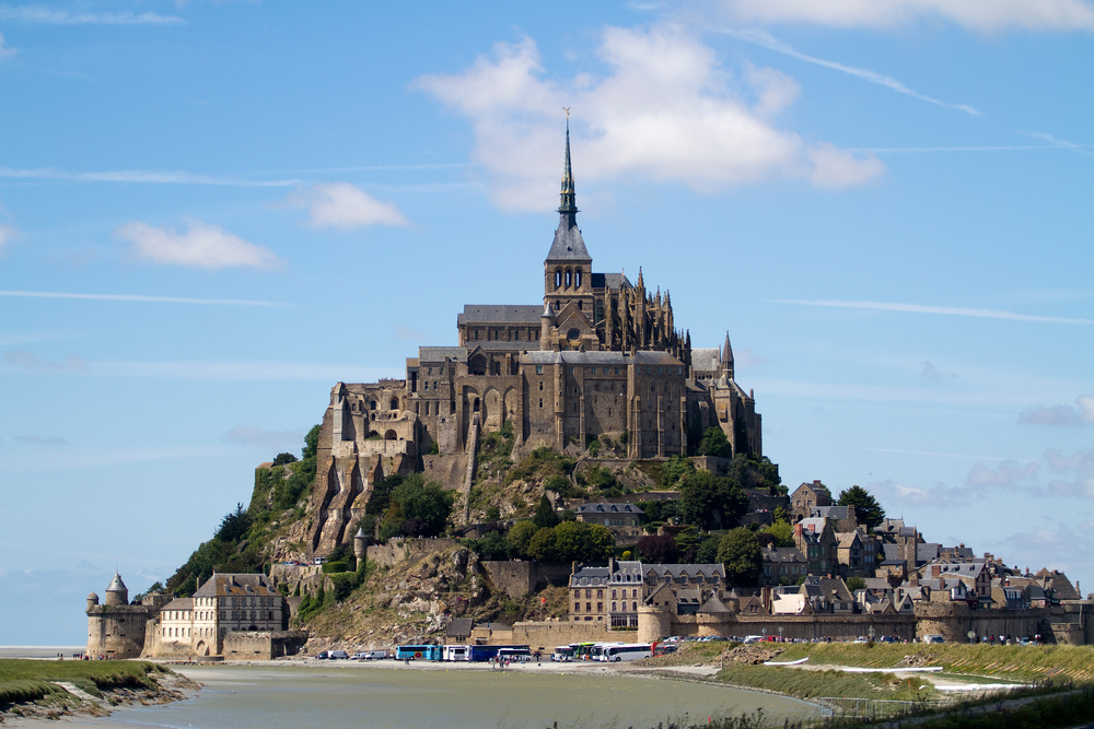 Mont St Michel taken from across the water with a blue sky in the background. 