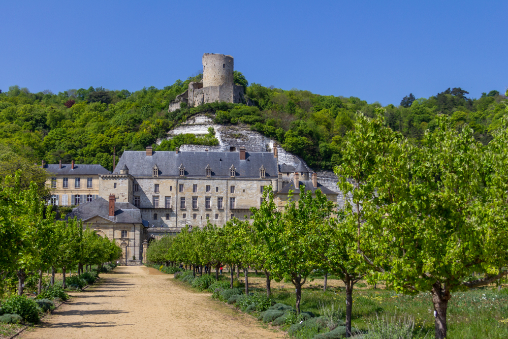 The tower of Chateau de La Roche-Guyon is perched atop the hill above the new chateau and garden. It is surrounded by trees. 