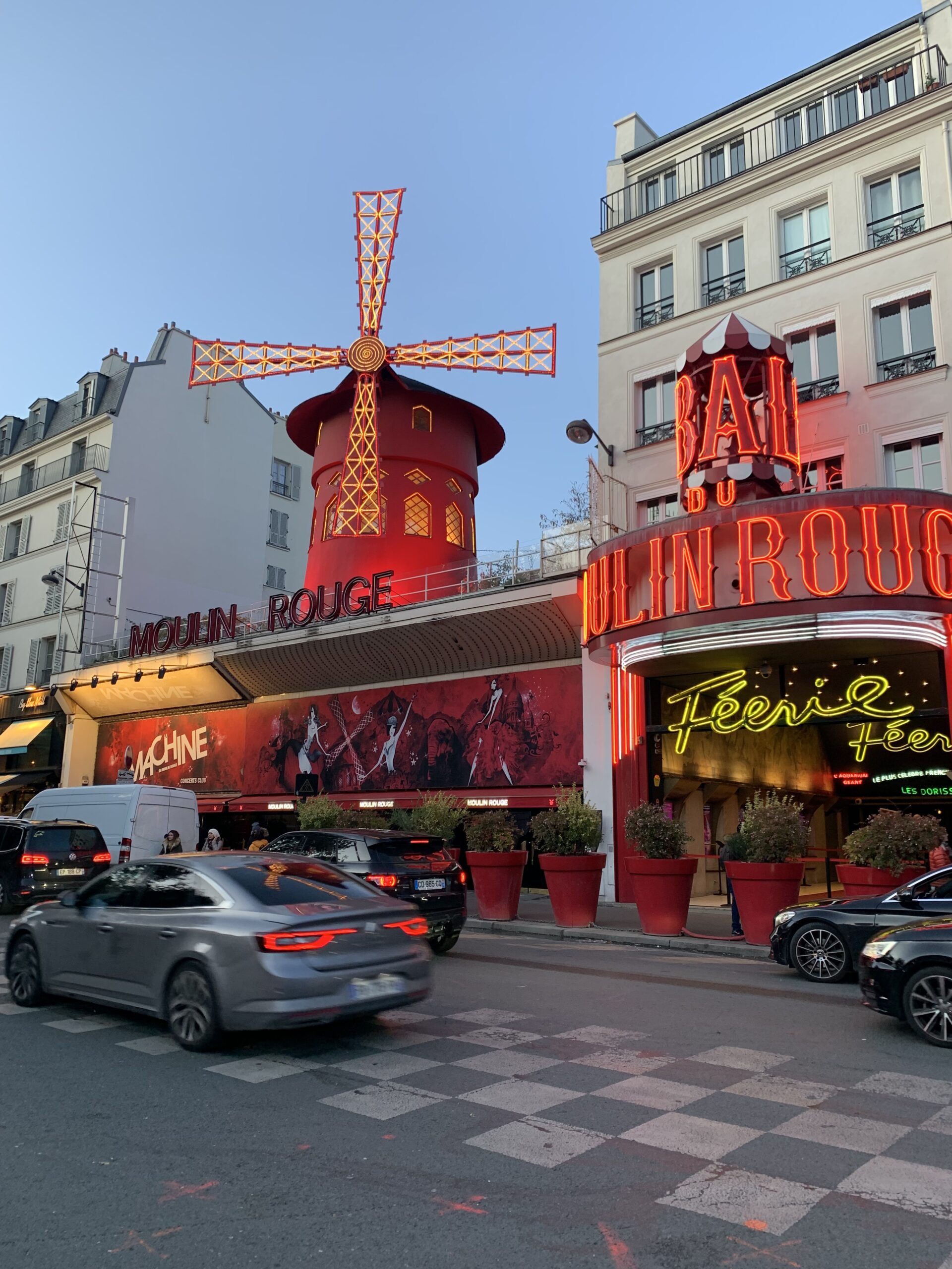The Moulin Rouge lit up at night from the outside. You can see the windmill and the building. 