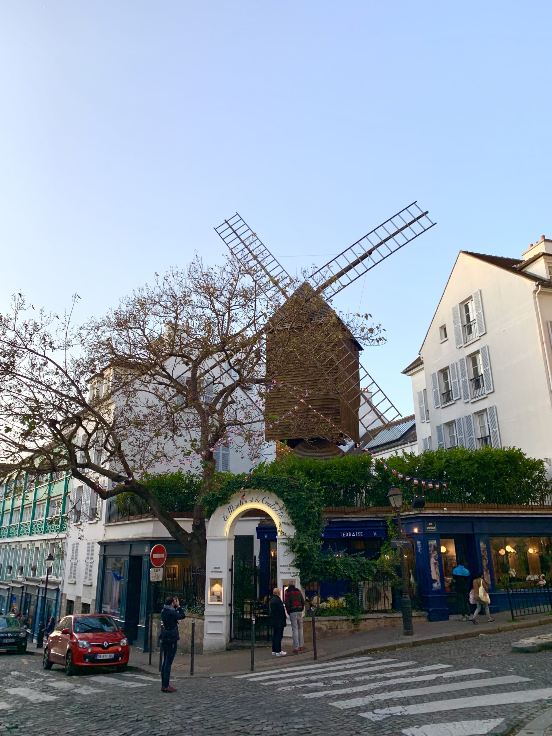 A windmill above a restaurant that is blue. This is one of the things to do in Montmartre.