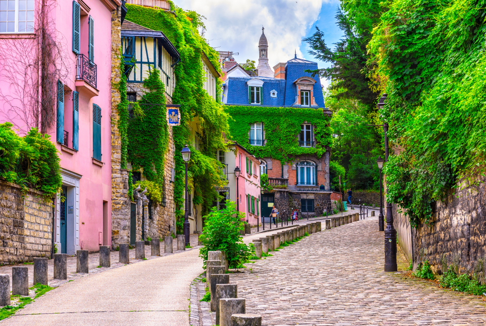 Street in Paris, France with a pink building and lots of Ivy. The article is about things to do in Montmartre.
