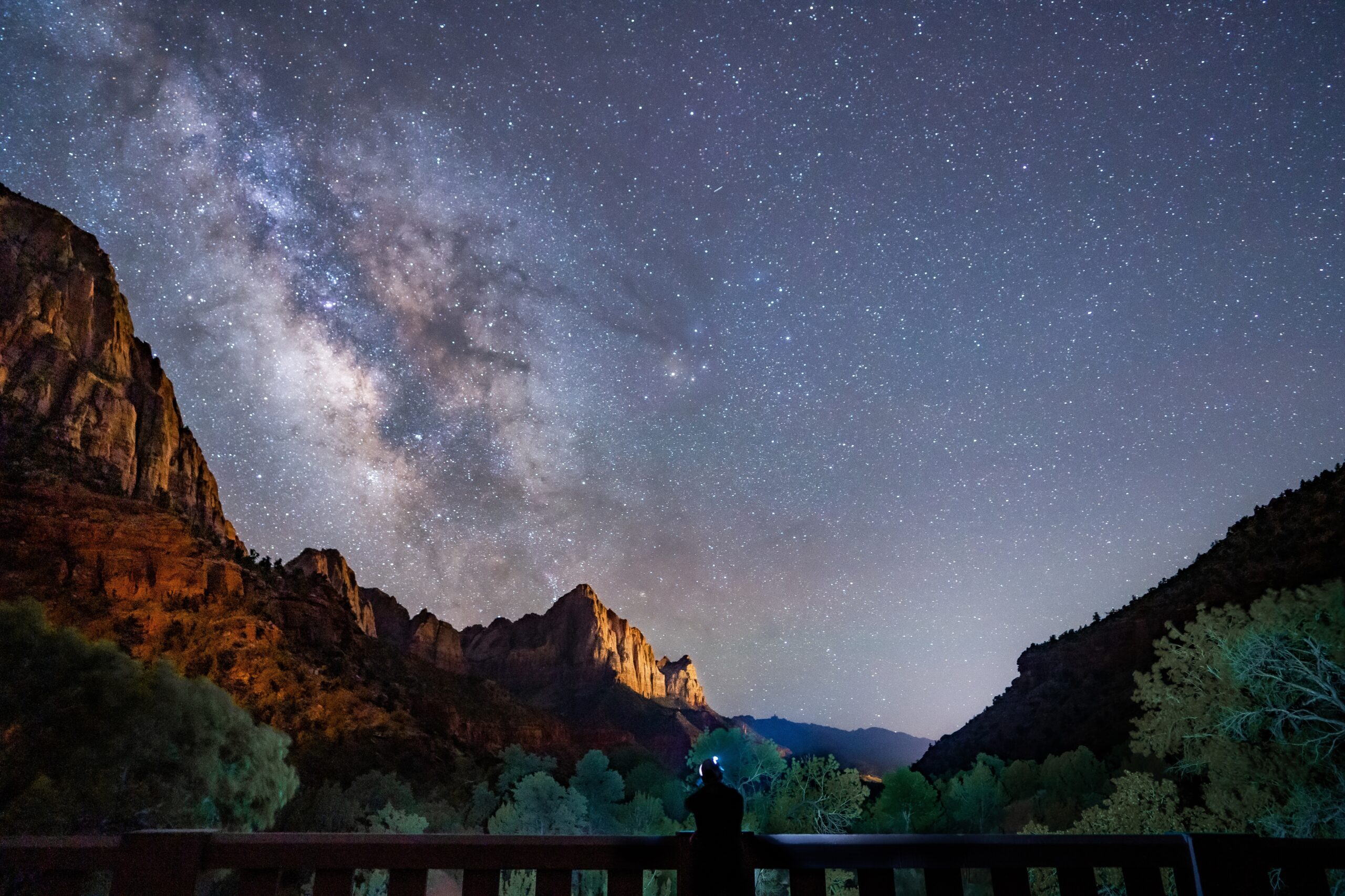 View of a person stargazing from a bridge at the Milky Way in Zion 