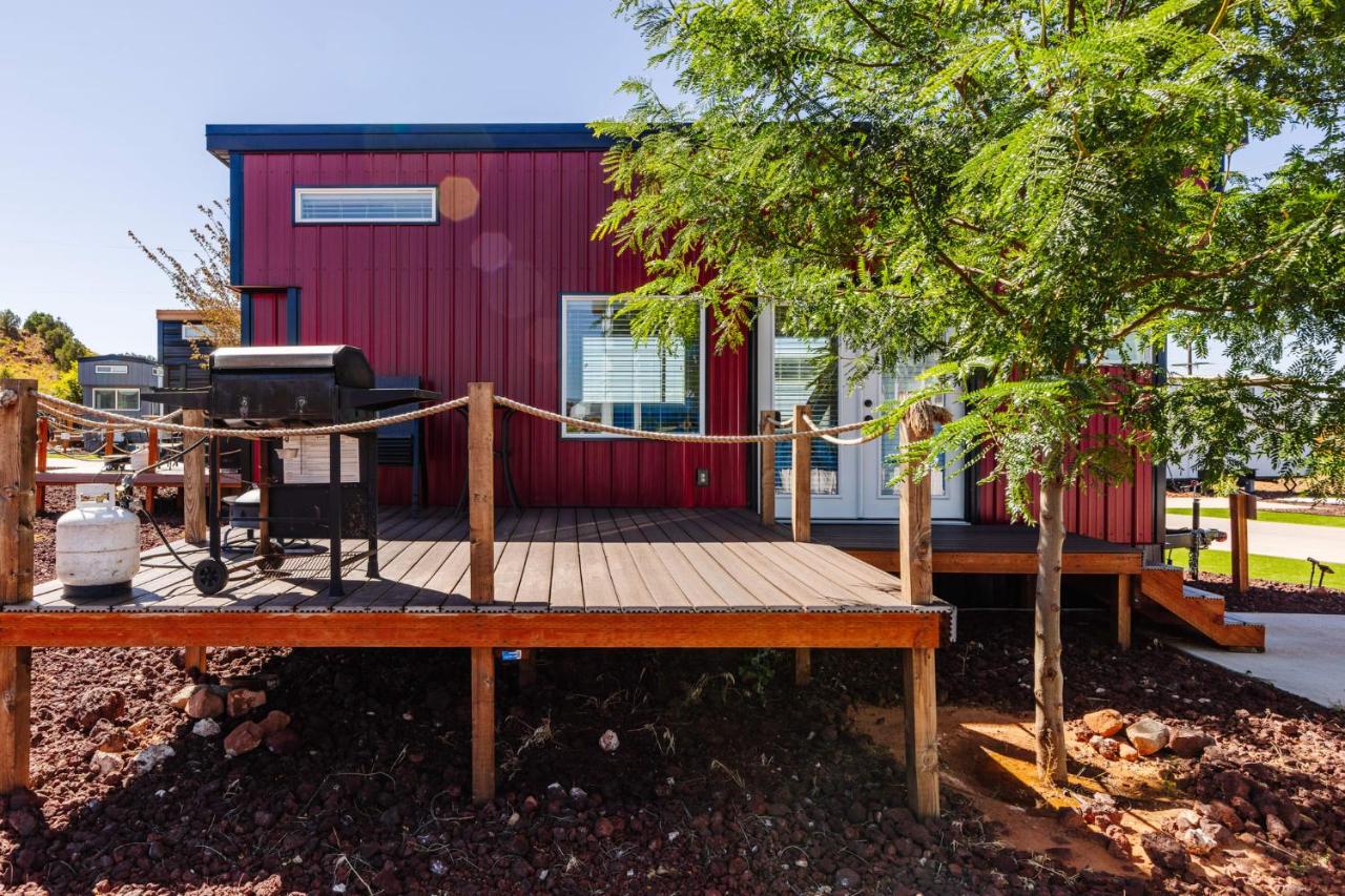 View of a cozy red Tiny House with a spacious deck and outdoor BBQ