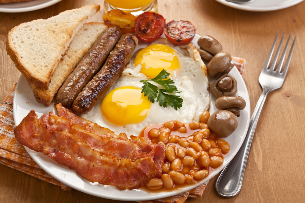 A traditional English breakfast includes sausage, eggs, tomatoes, mushrooms, bread, and baked beans.