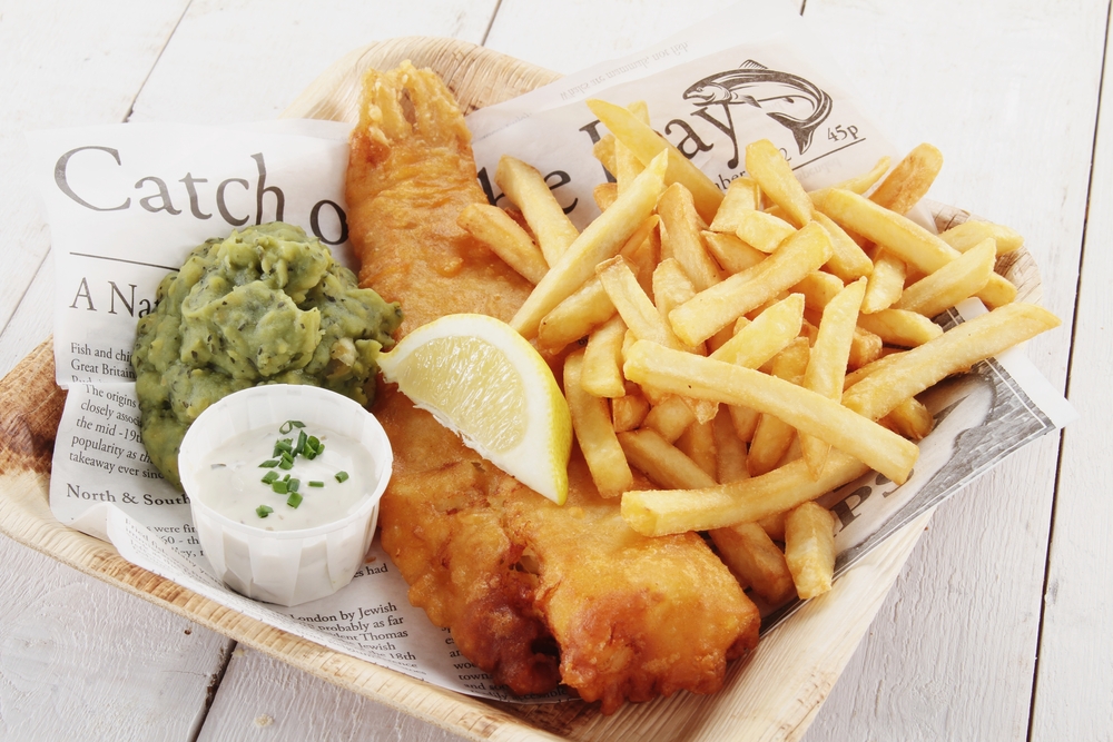 A pllate of fish and chips with mushy green peas