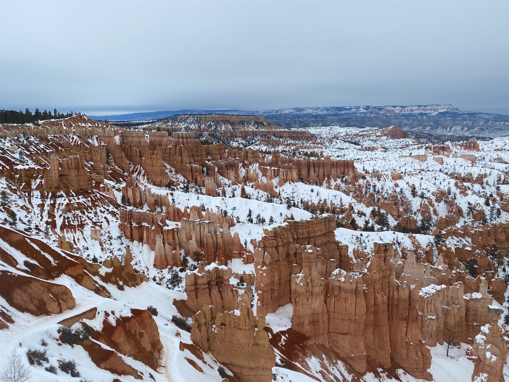 Cloudy view over Bryce Canyon with hoodoos and snow.
