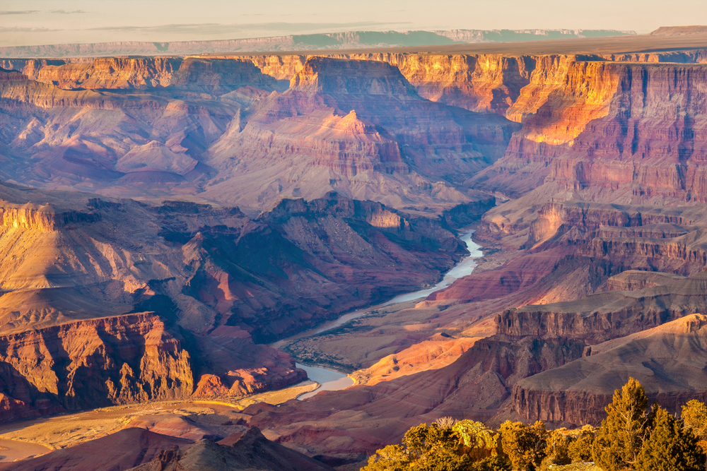 Sunset over the rugged and colorful Grand Canyon with a river in the bottom.