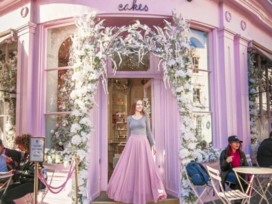 a girl in pink skit standing in front of a British bakery