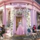 a girl in pink skit standing in front of a British bakery