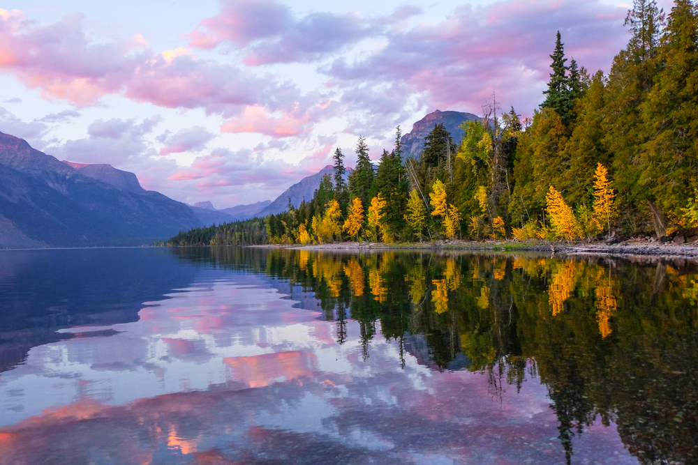 Vivid sunset reflecting in Lake McDonald with mountains and fall trees.
