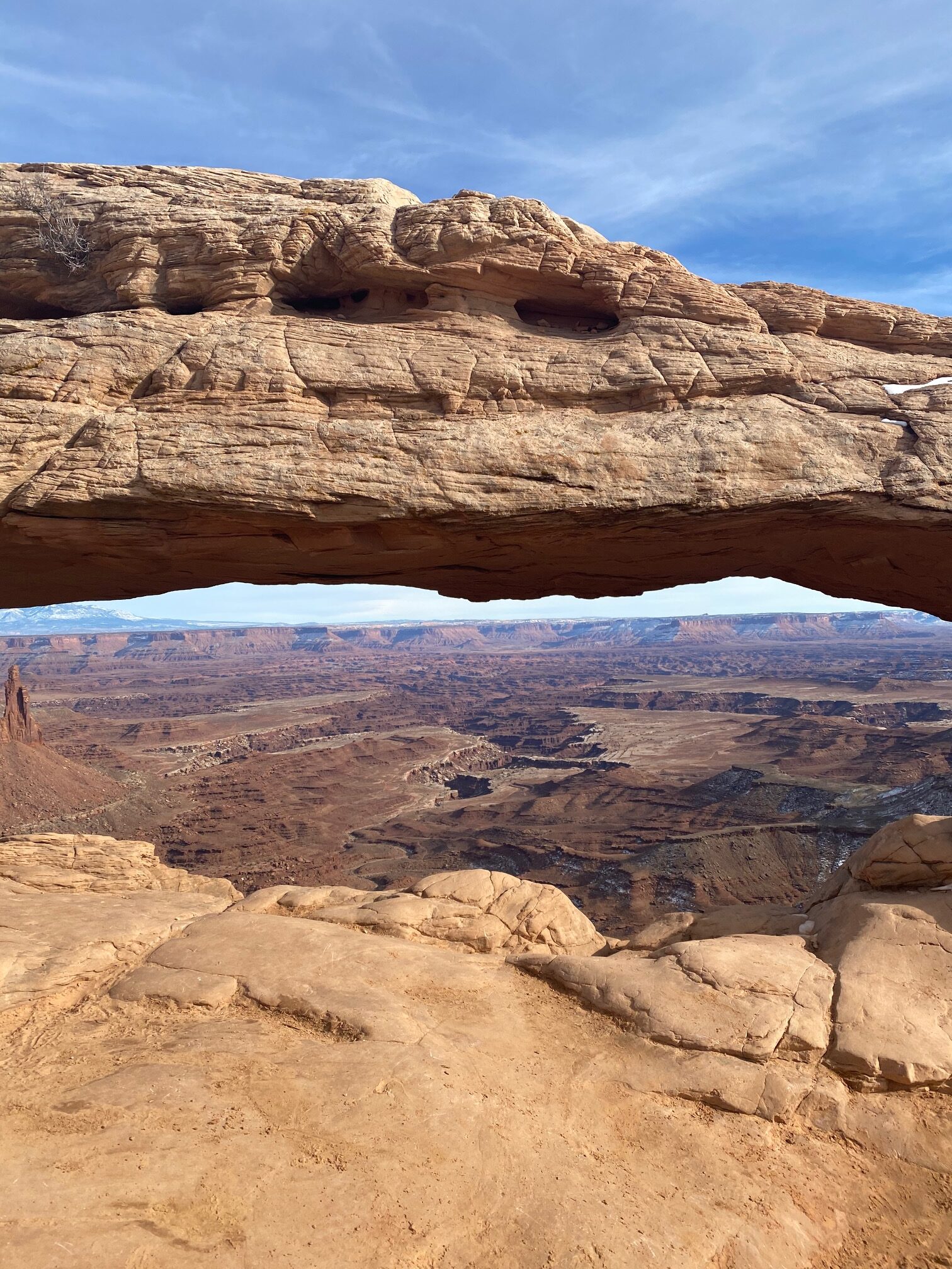 View through Mesa Arch of the vast Canyonlands National Park with canyons and mesas.
