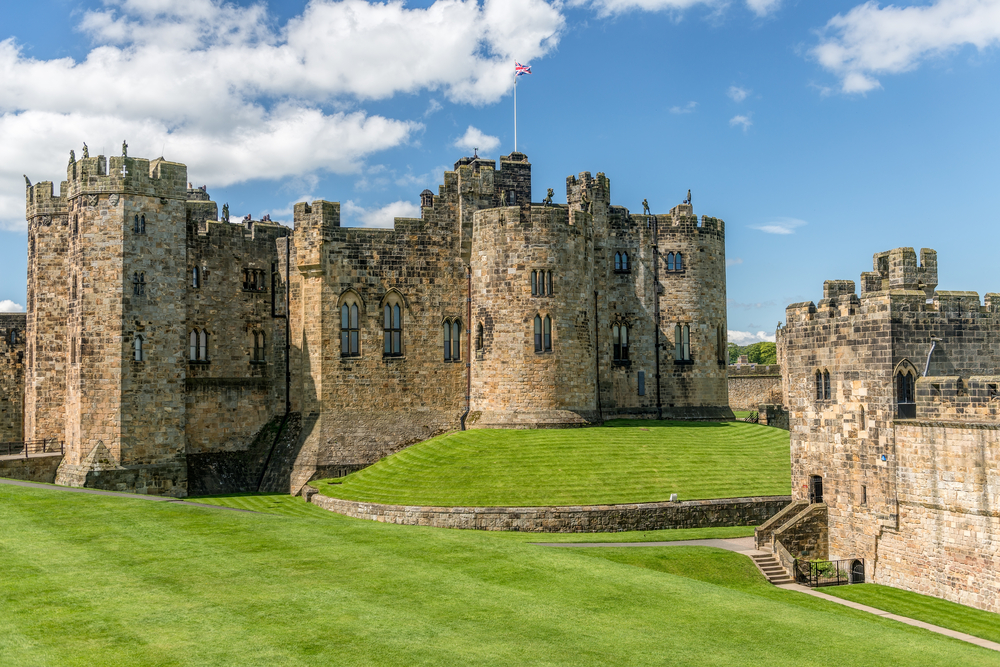 Alnwick Castle showing the castle on a small hill surrounded by grass. 