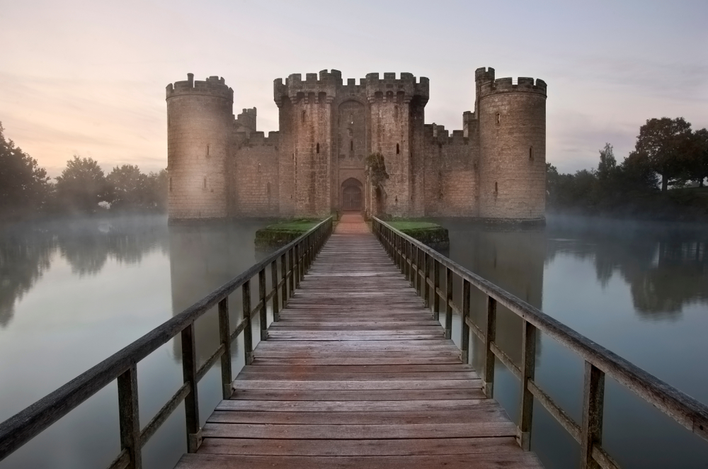 Medieval moat and Bodiam Castle landscape image during misty foggy Autumn morning. 