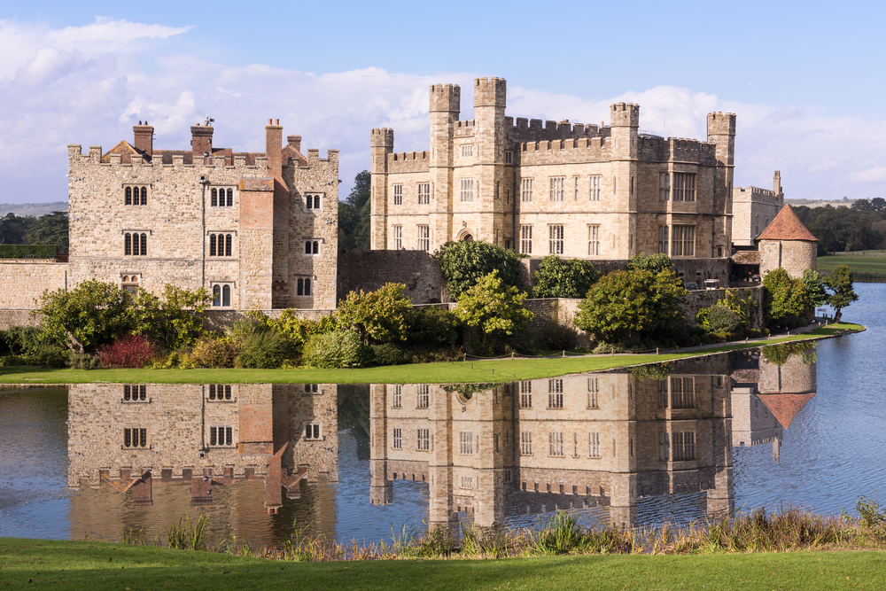 Leeds castle surrounded by trees and a moat. The castle is reflected in the water. One of the best castles in England. 