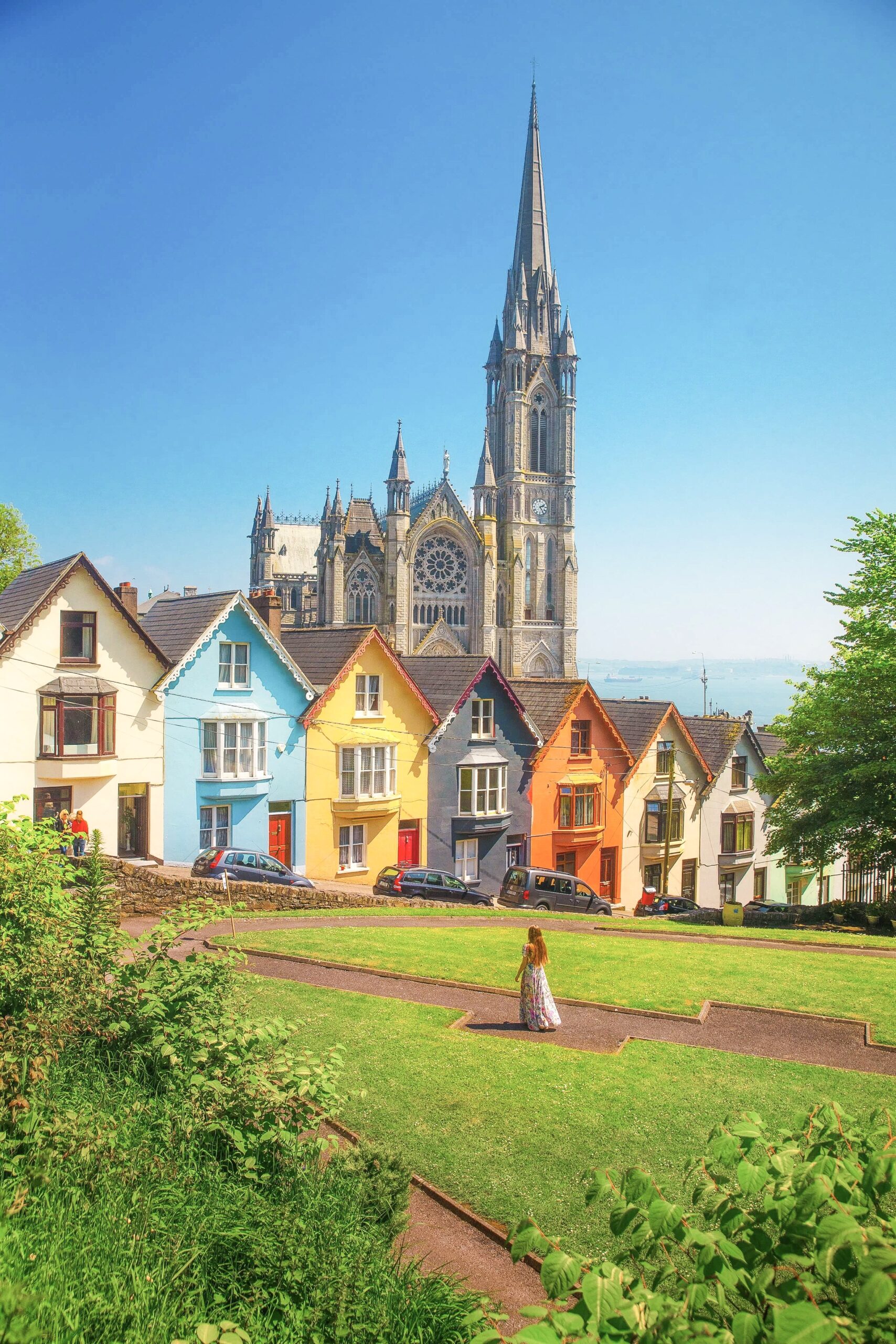 a woman stands in front of a row of houses on a sunny day in Ireland, one of the best places to visit in Europe in June