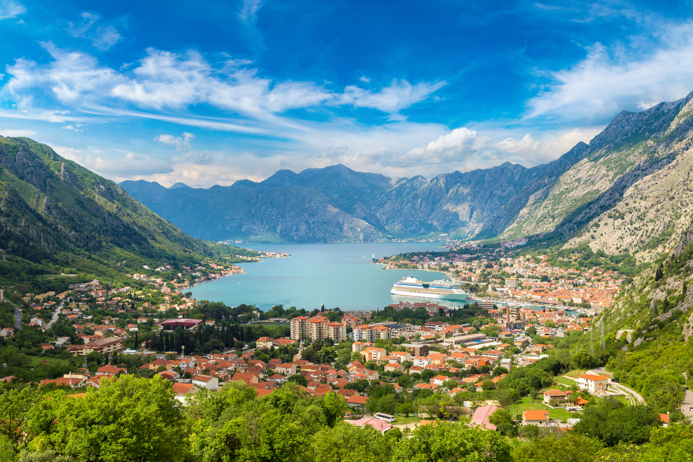 lake in a valley with mountains on three sides, a town is next to the water, there are a lot of trees around the buildings