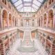 woman standing in a pink skirt on stairs in vienna austria. the whole scene is indoors with a glass roof