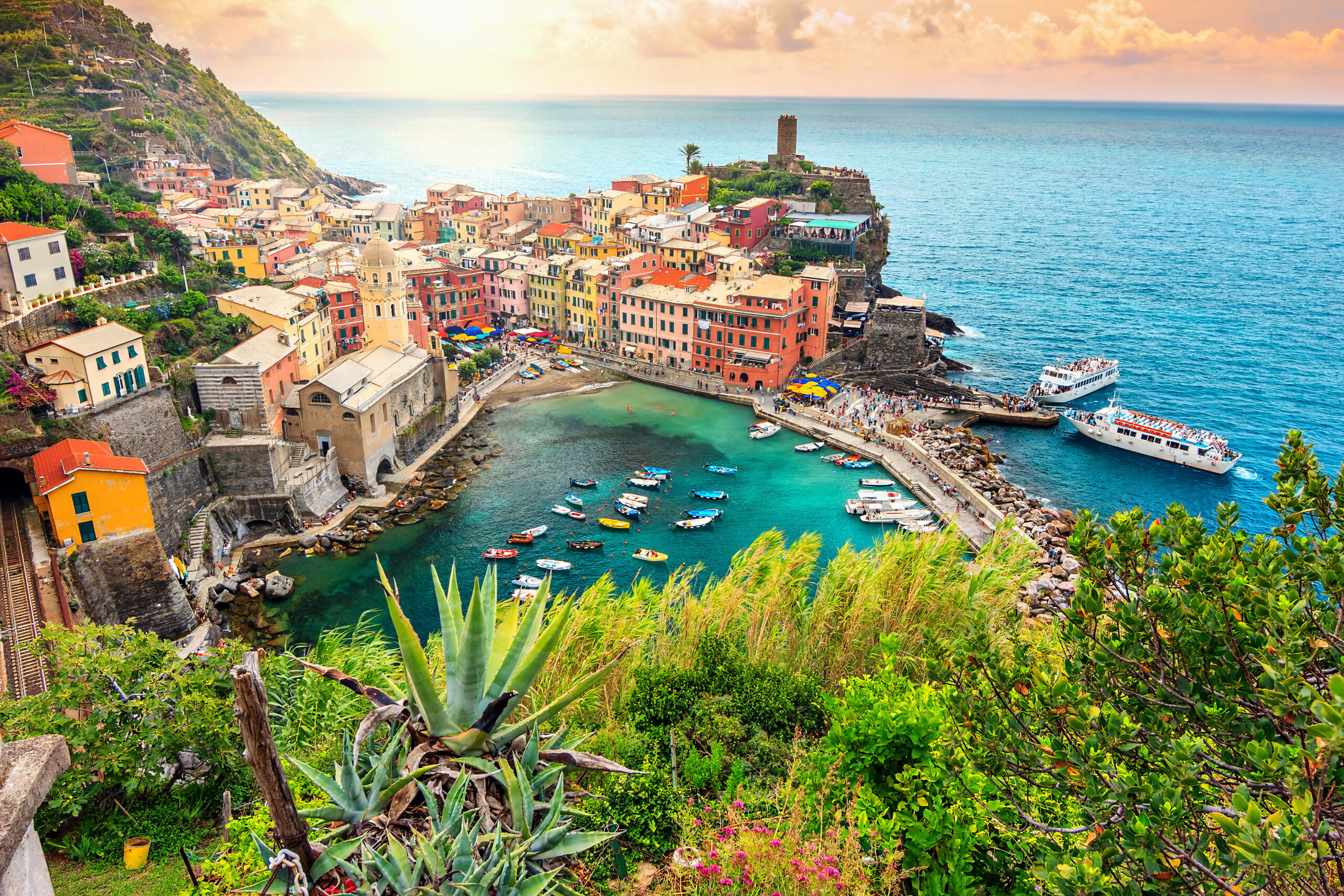 Amazing view of a colorful Cinque Terre beach and village surrounded by greenery, mountains, and little boats 