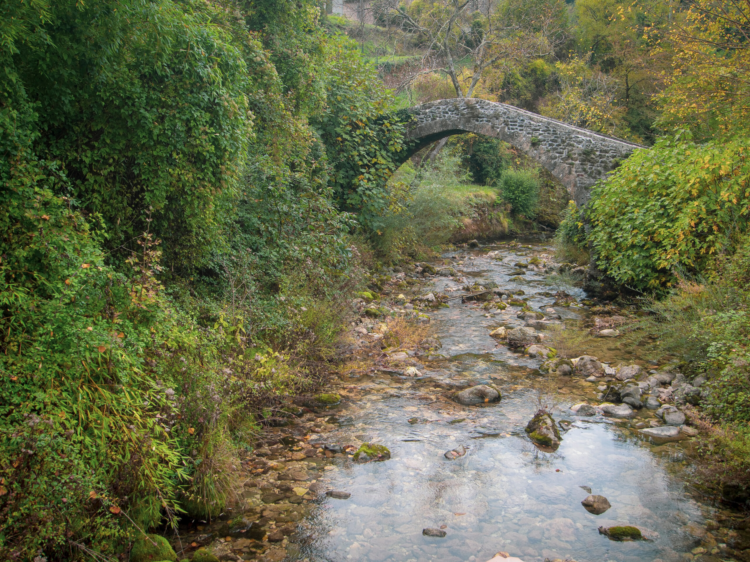 View of a beautiful ancient arched bridge over Catenelle Stream near the Bozzeti Thermal Baths in the fall foliage 